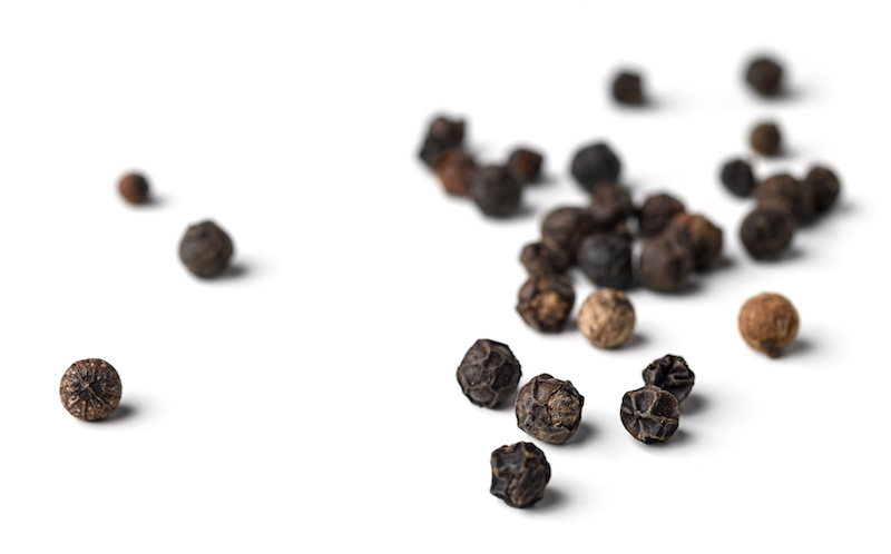Close-up image of black pepper on white background